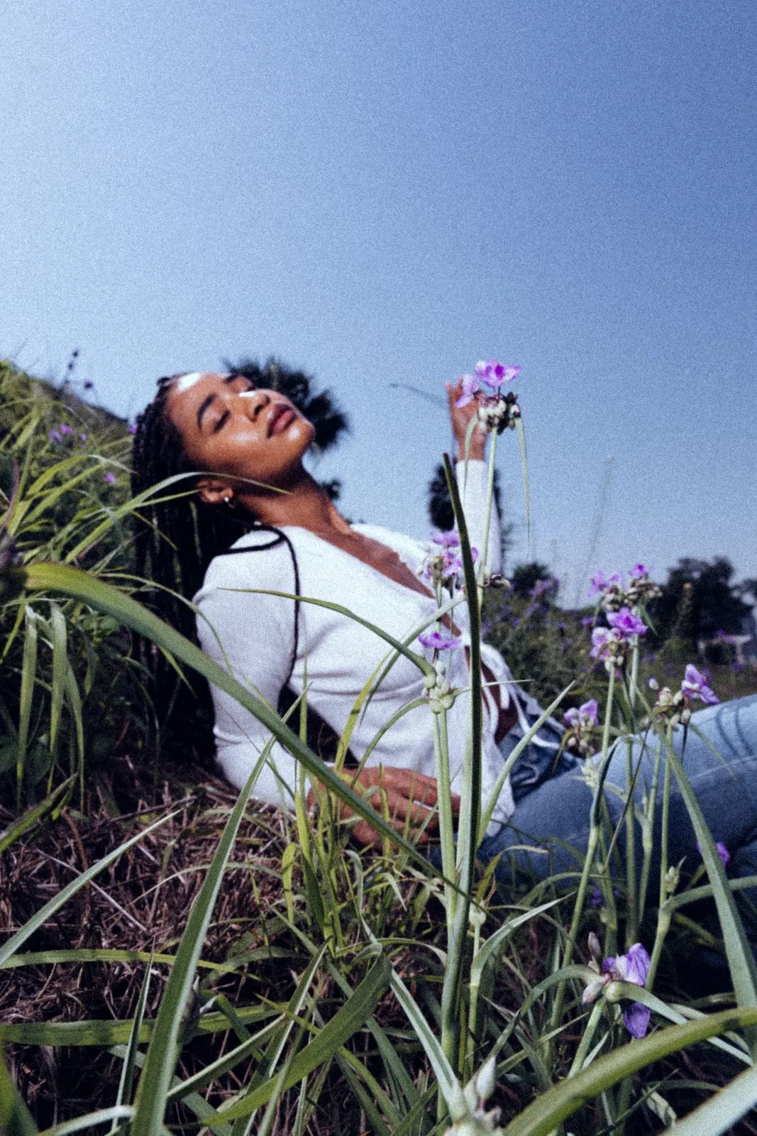 Mujer descansando sobre el césped entre flores